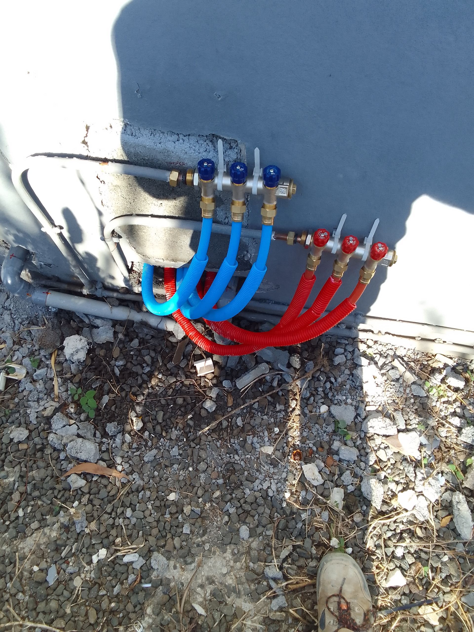 Installation de plomberie extérieure avec tuyaux bleus et rouges connectés.