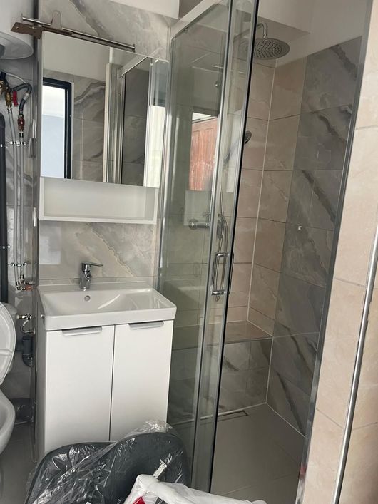 Petite salle de bains avec meuble lavabo blanc et cabine de douche en verre.