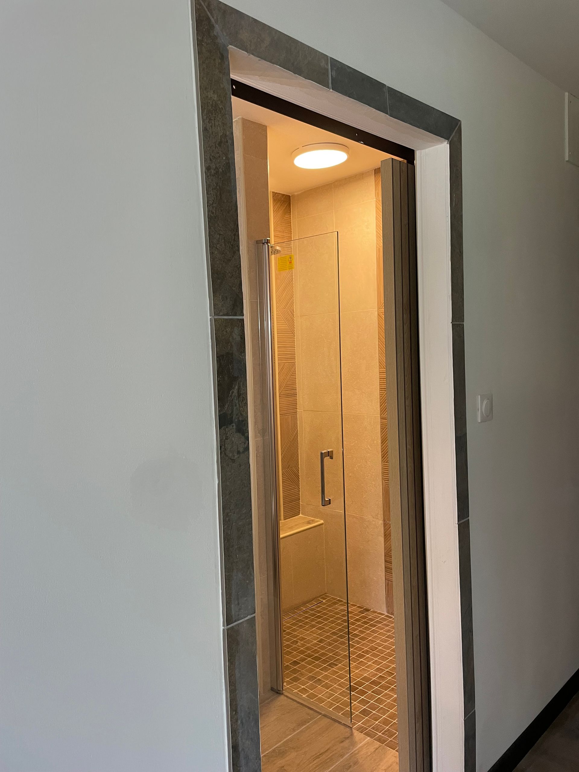 Entrée d'une salle de bains avec vue sur une douche à l'italienne vitrée.