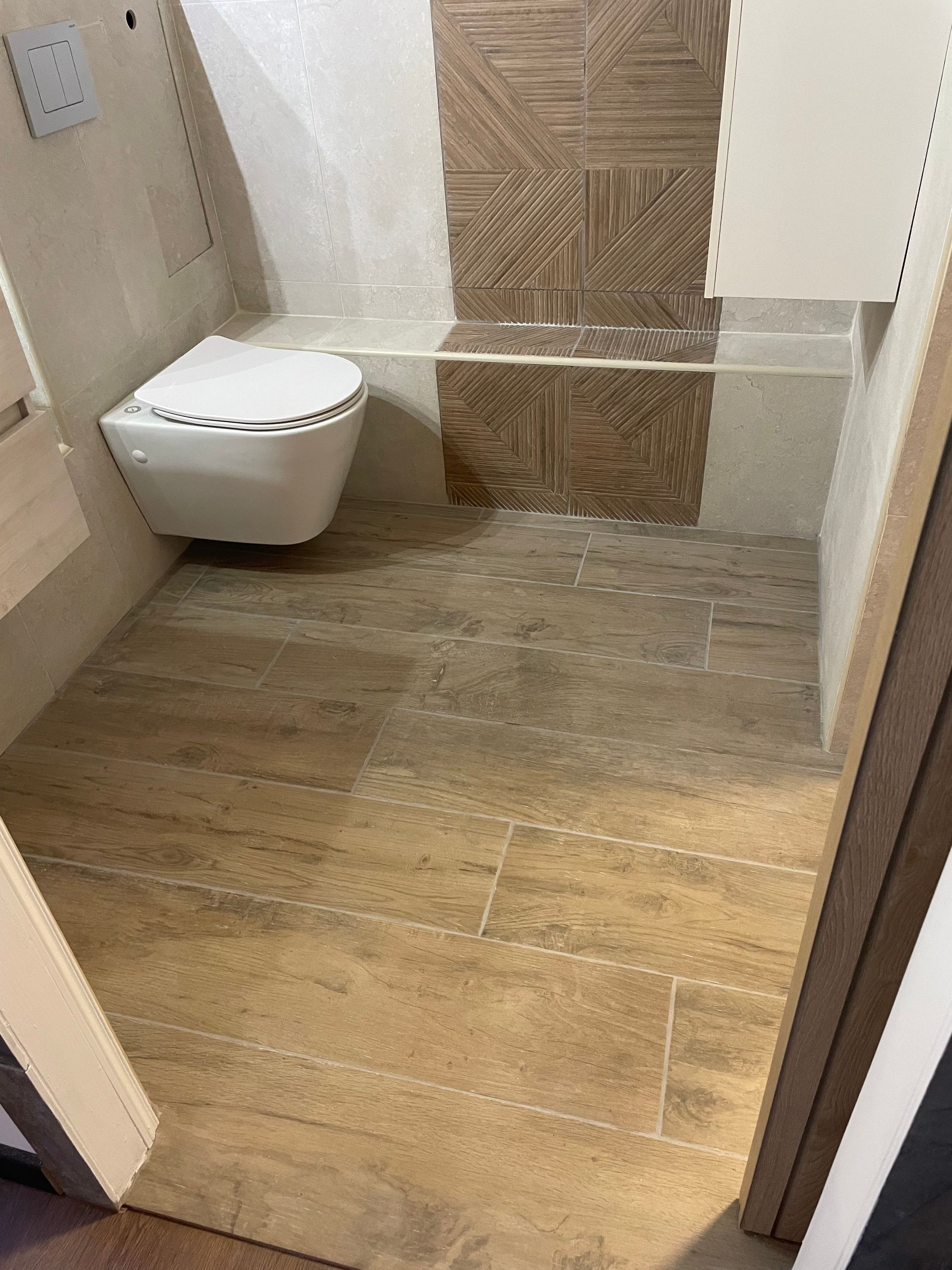 Petite salle de bains inachevée avec toilettes, carrelage imitation bois.