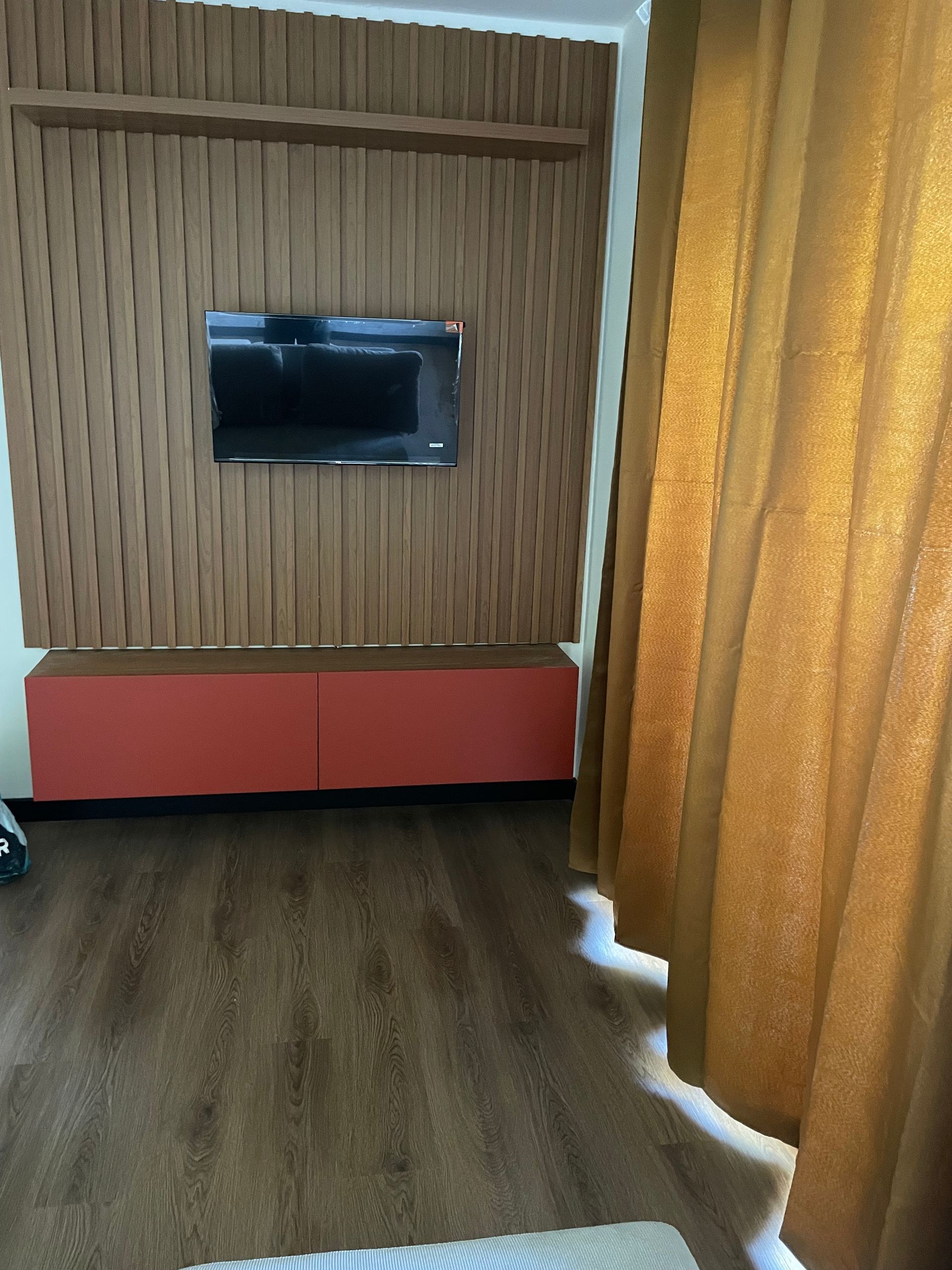 Petit salon avec télévision murale avec revêtement mural en bois et parquet au sol.