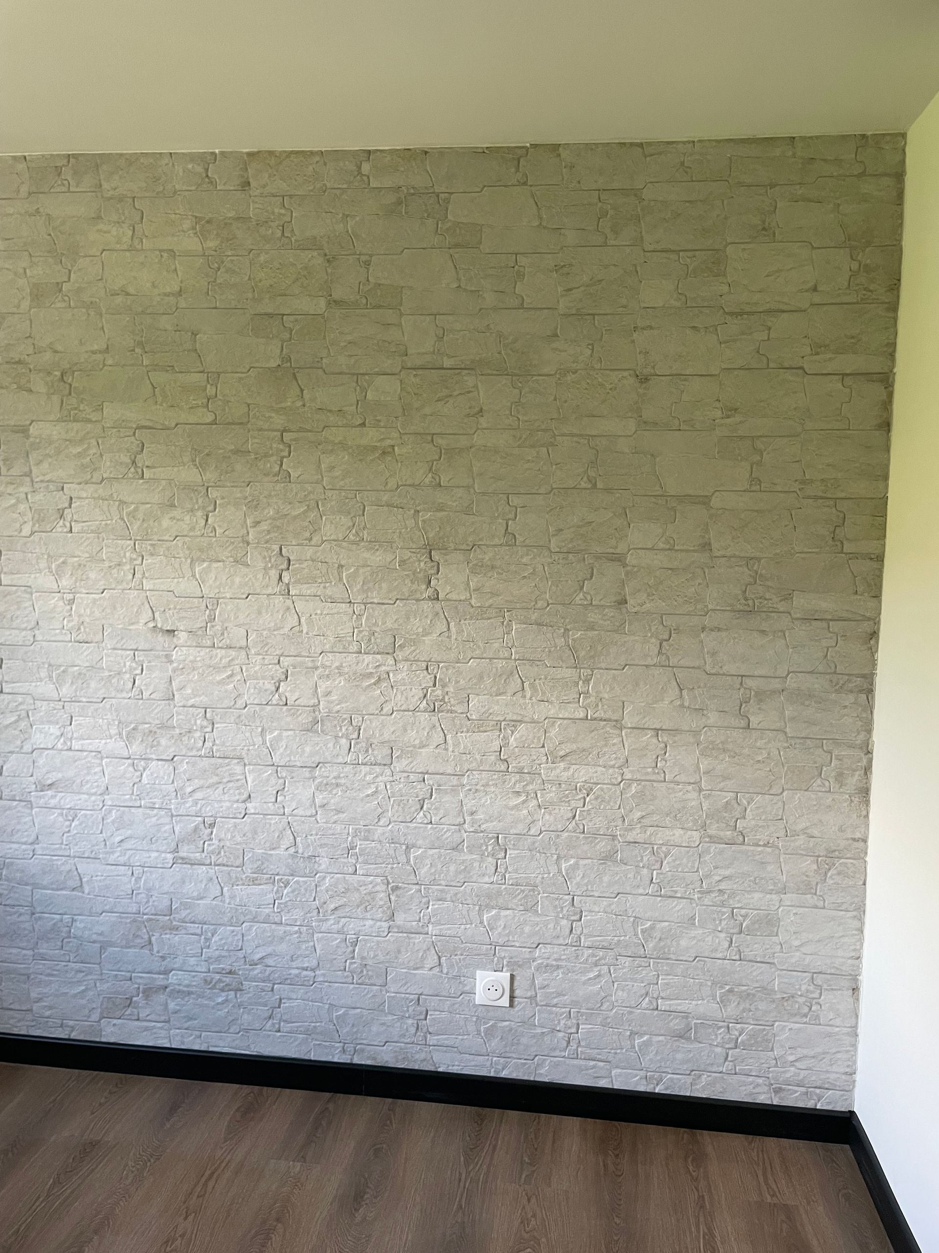 Pièce vide rénovée avec parement en pierre et parquet.