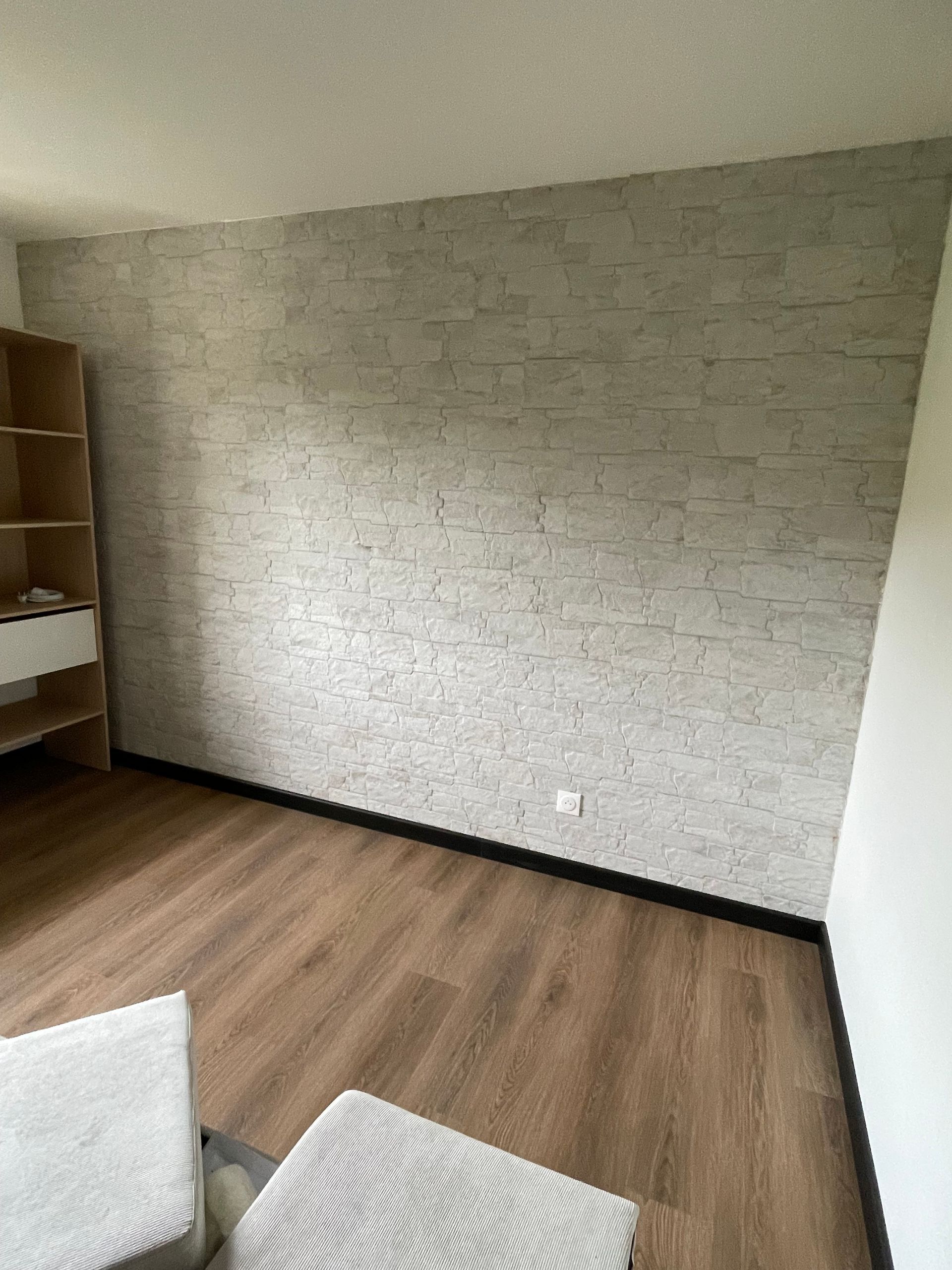 Chambre vide avec un mur en pierre et du parquet.