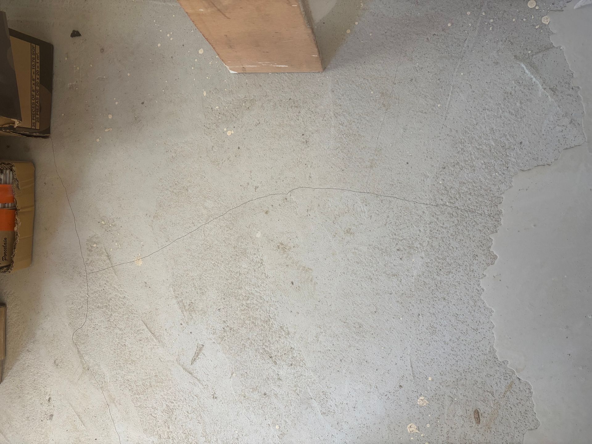 Un sol en béton abîmé est préparé pour la pose d'un parquet.