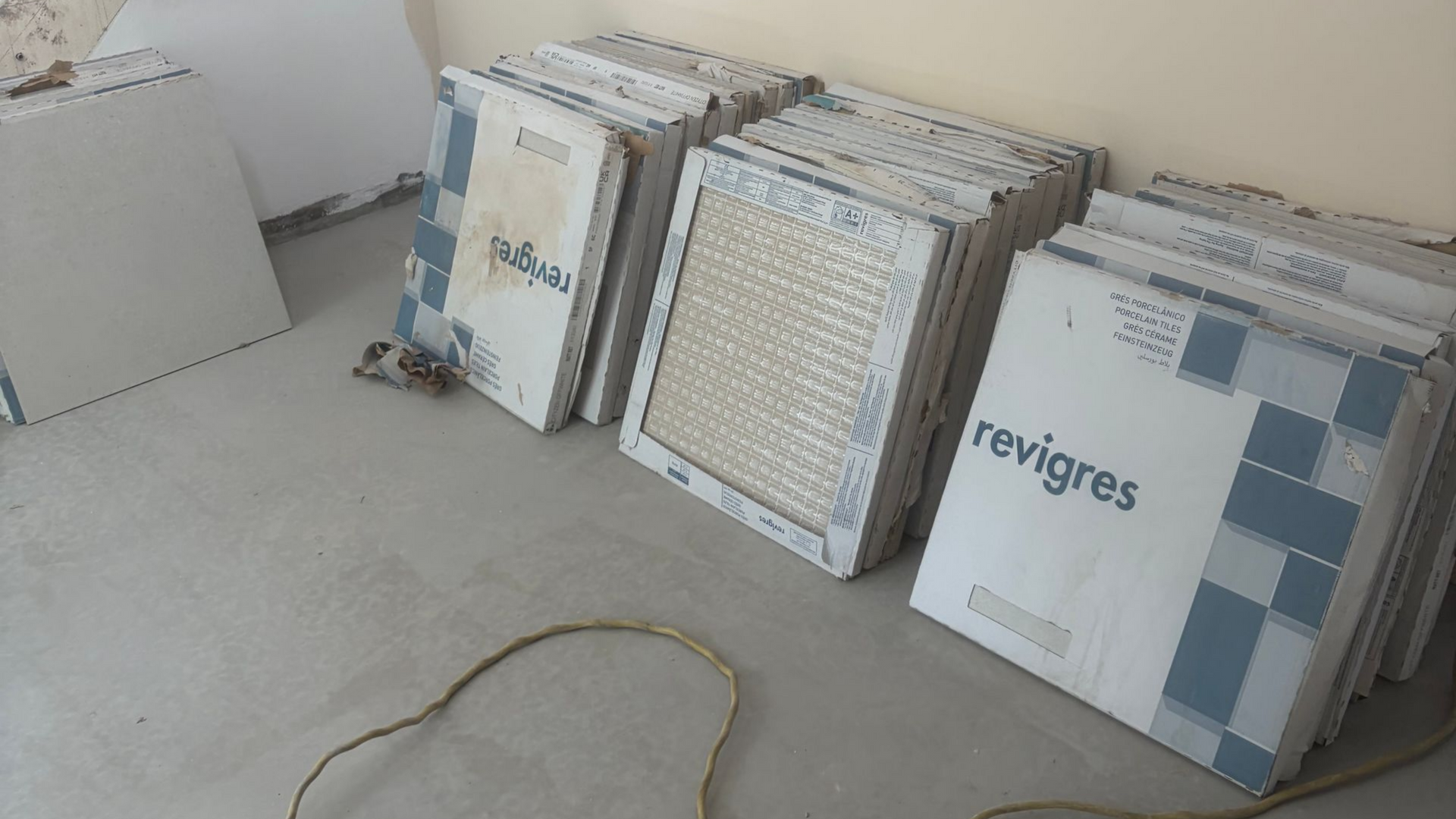 Échantillons de carreaux empilés, appuyés contre un mur sur un sol en béton.