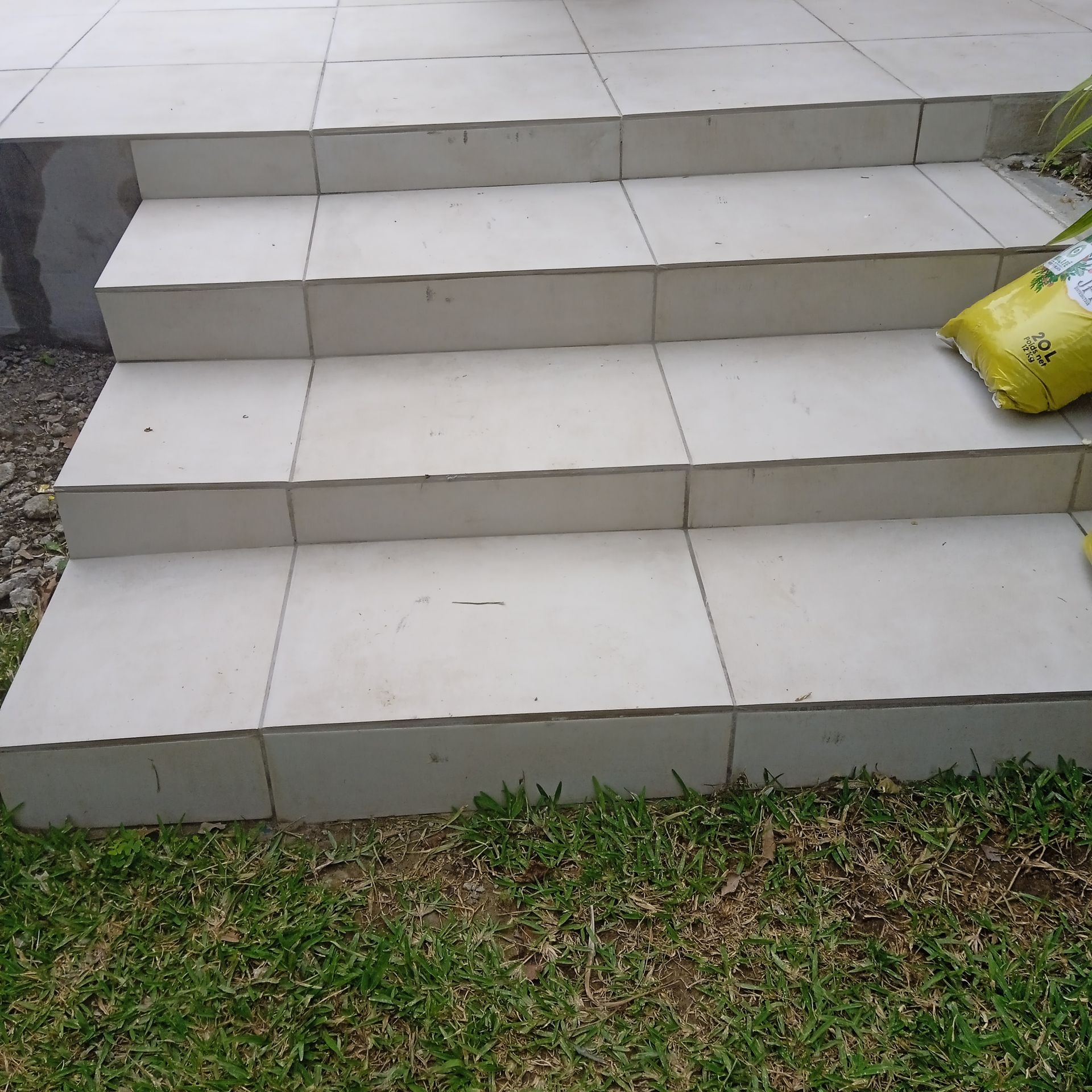 Des marches extérieures en carrelage blanc sont entourées de pelouse.