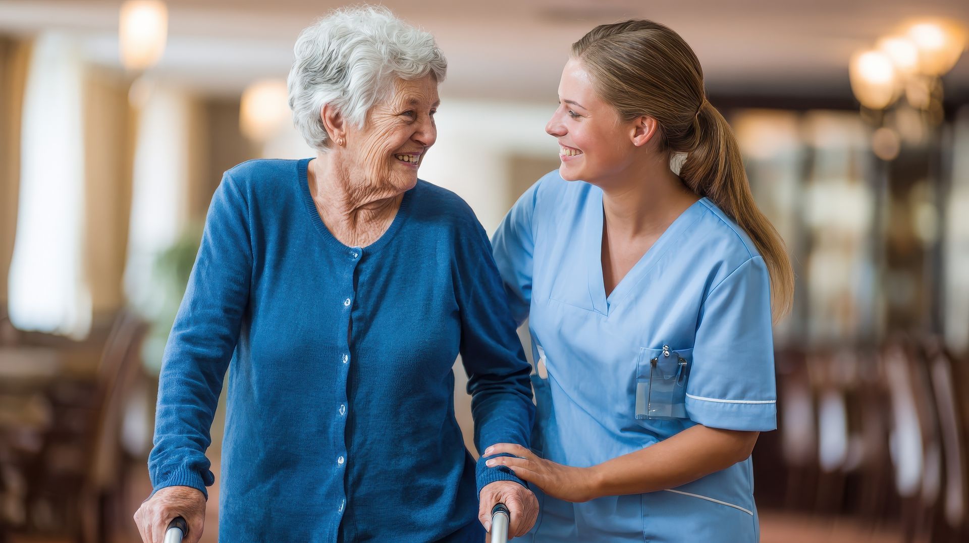 Une femme avec un déambulateur et un soignant marche et sourit dans un établissement bien éclairé.