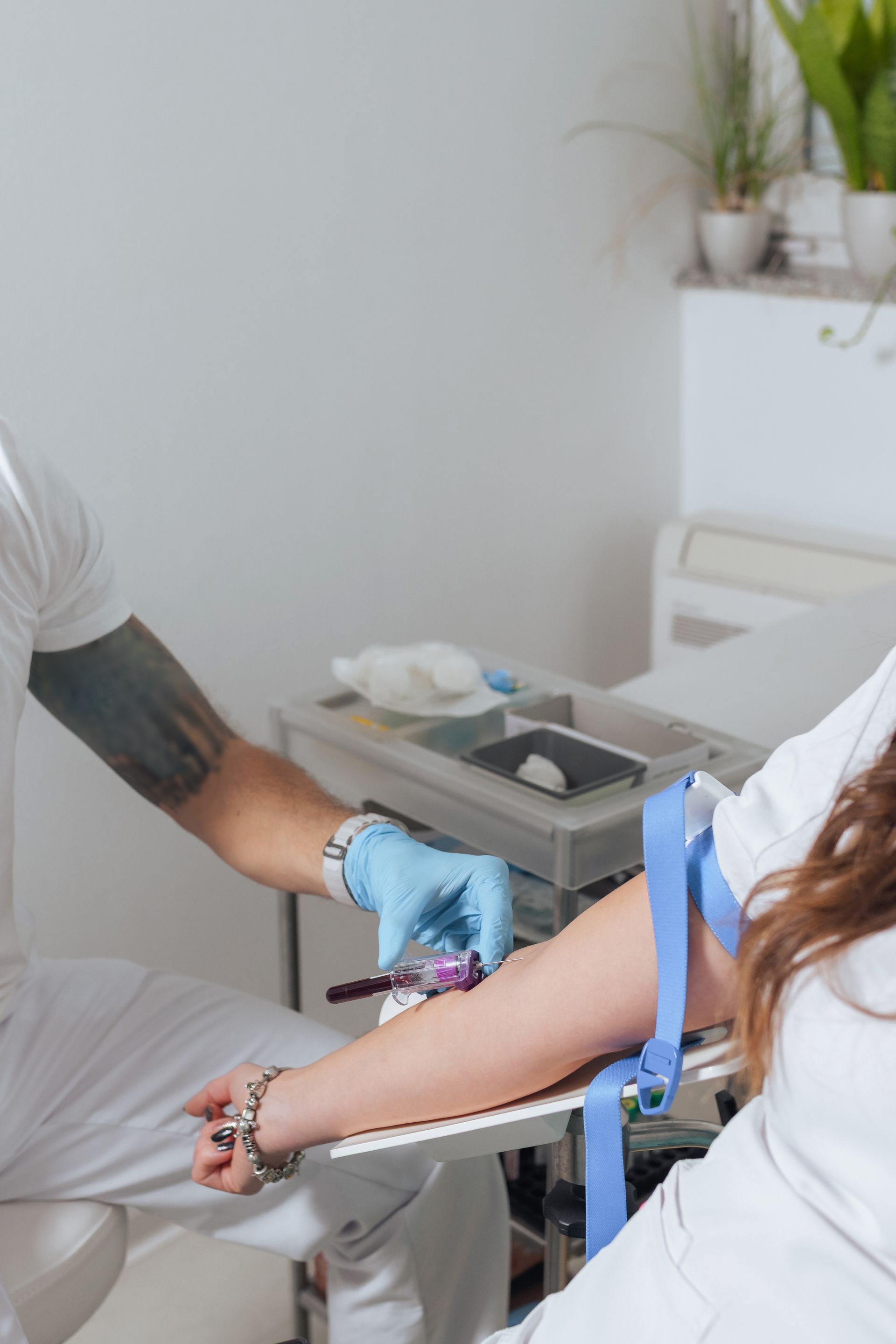 Une personne prélève du sang du bras d'une autre personne dans un contexte médical.