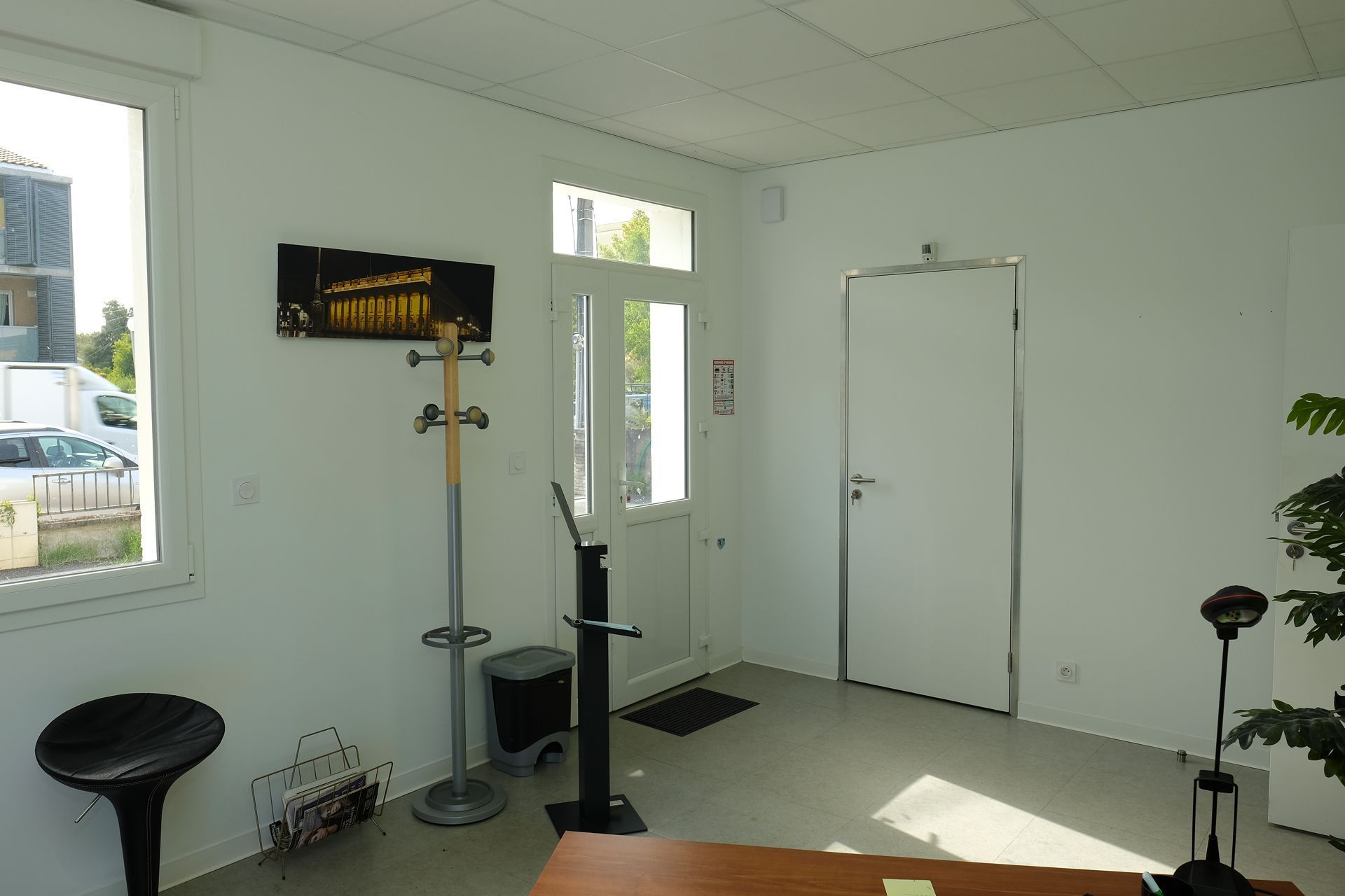 Intérieur de bureau avec bureau, chaises, porte vers l'extérieur et œuvres d'art.