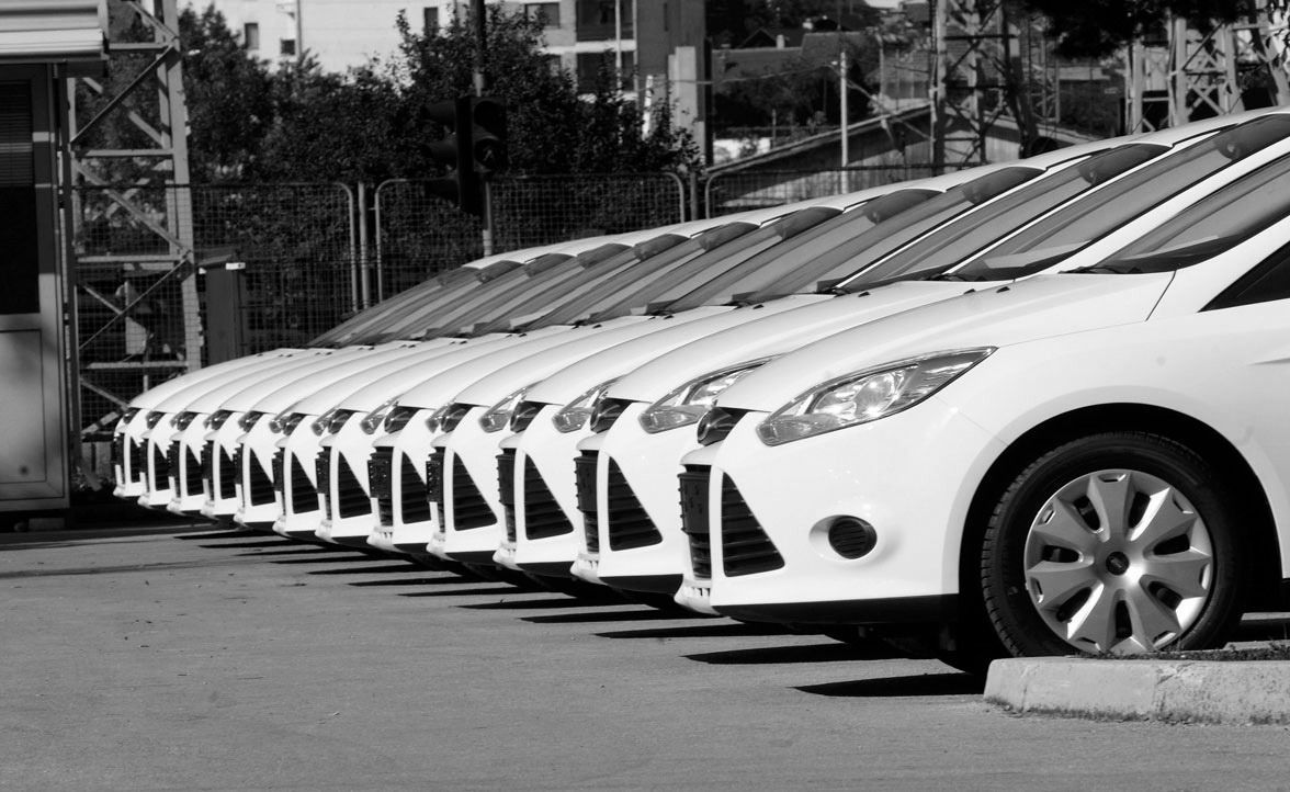 Fila de coches blancos aparcados en un estacionamiento.