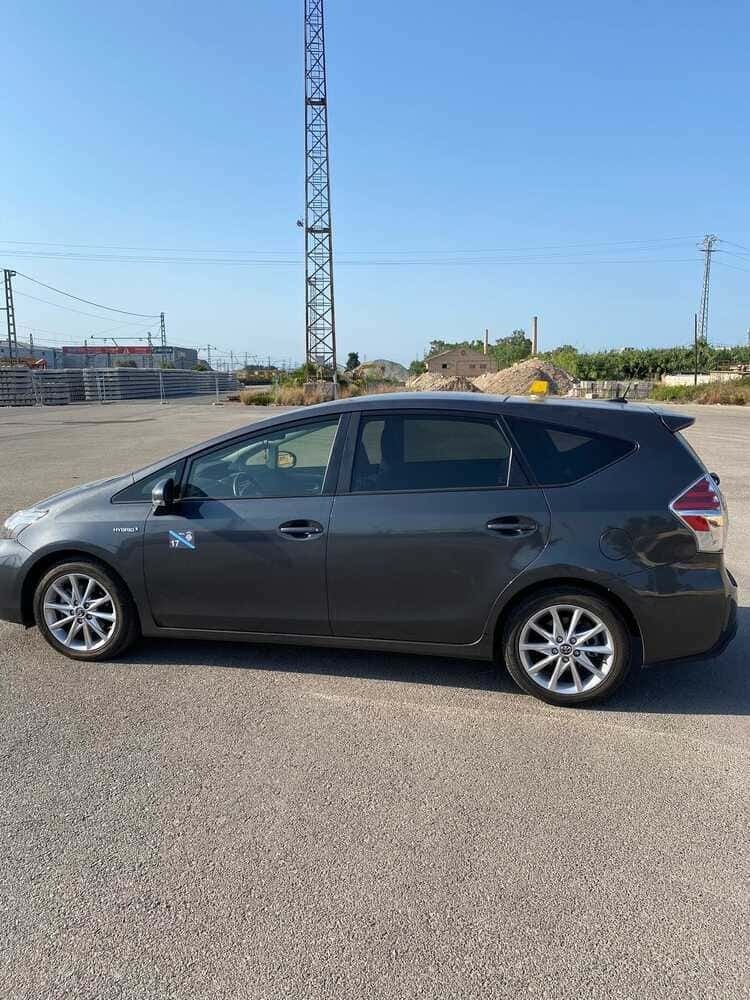 Toyota Prius V gris estacionado en un estacionamiento al aire libre en un día soleado.