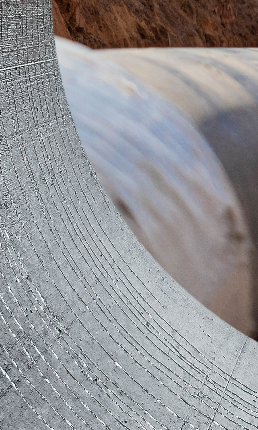 Gros plan sur un grillage avec, en arrière-plan, des rouleaux de balles de foin emballées, de forme floue.