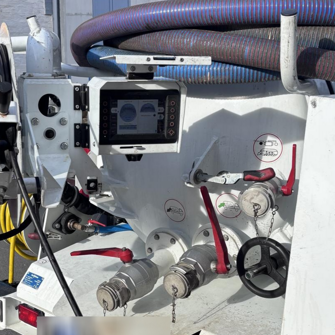 Gros plan sur une machine industrielle blanche avec des tuyaux, des vannes, un tamis et un tuyau bleu.