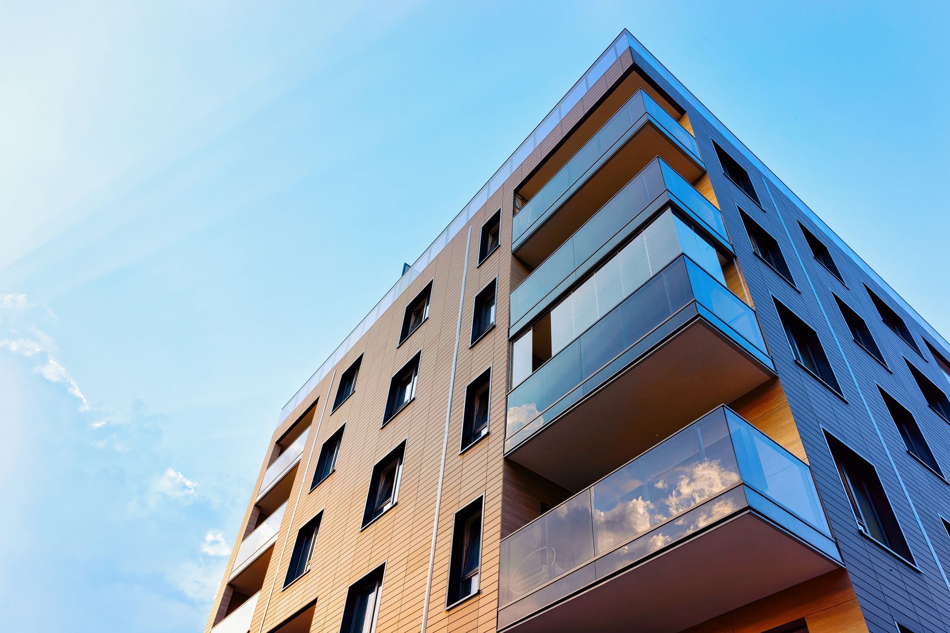 Immeuble en briques à plusieurs étages avec balcons se détachant sur un ciel bleu clair.