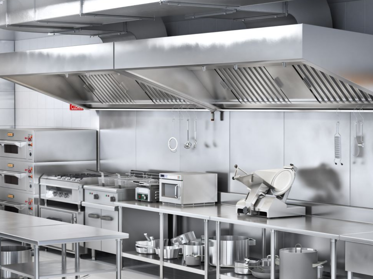 Cuisine professionnelle équipée d'appareils en acier inoxydable, d'une hotte aspirante et de divers ustensiles de cuisine.