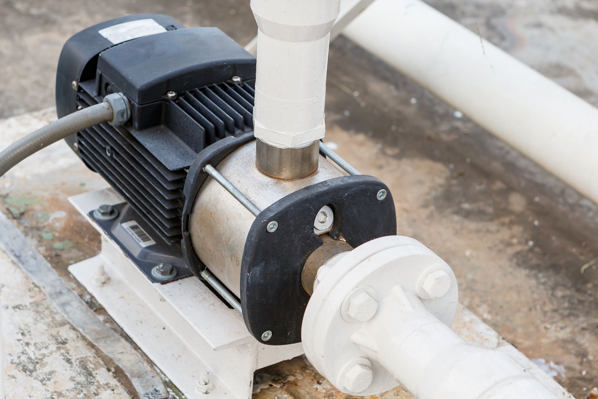 Pompe à eau électrique avec moteur noir et tuyaux blancs.