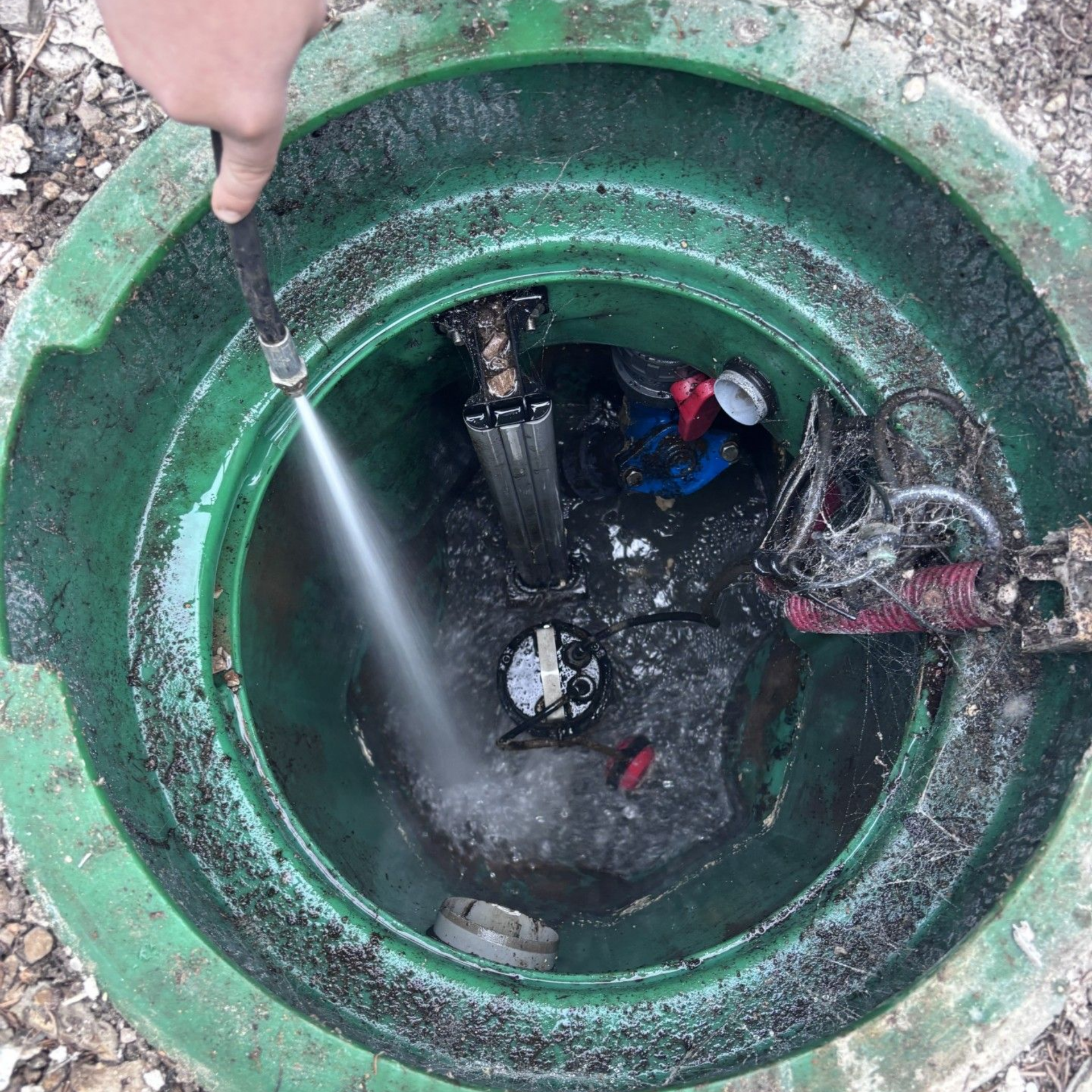 Pompe à eau raccordée à des tuyaux blancs, montée sur un socle métallique, à l'extérieur.