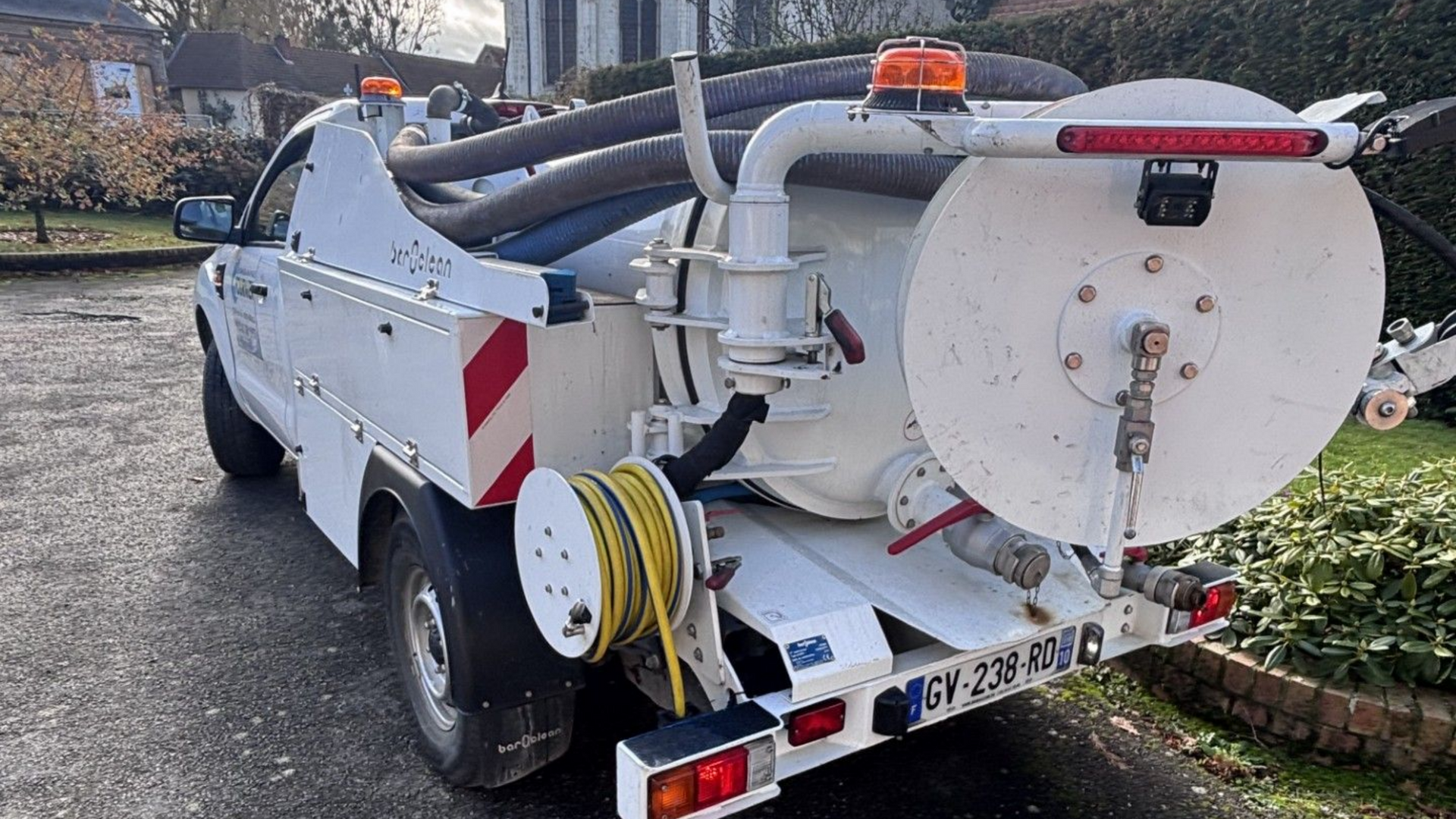 Trois personnes serrent des boulons avec des clés sur un système de tuyaux bleus à l'extérieur.