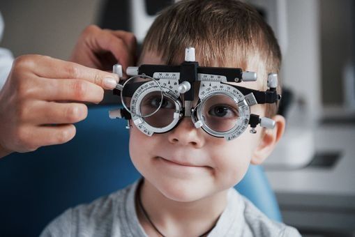 Un niño pequeño se hace revisar la vista por un oftalmólogo.