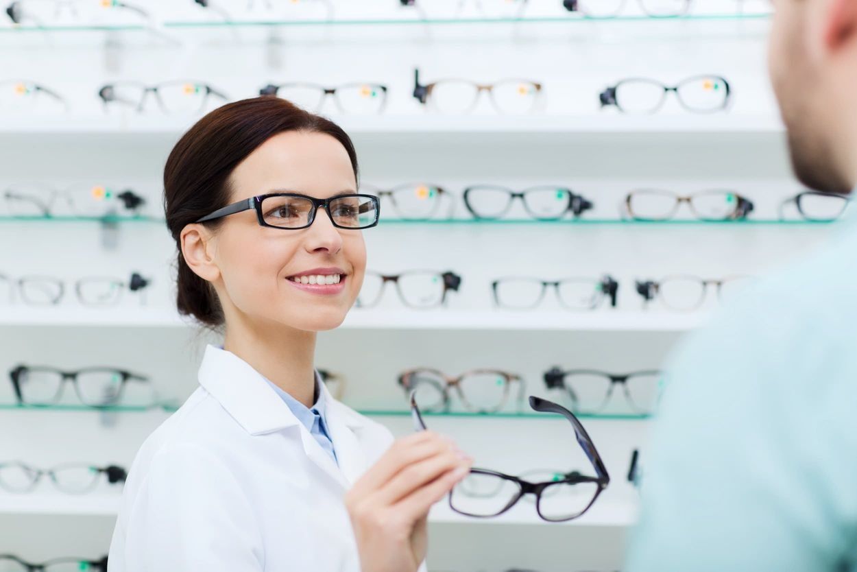 Una mujer que lleva gafas está hablando con un hombre en una óptica.