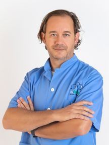 Un hombre con un uniforme azul está de pie con los brazos cruzados.