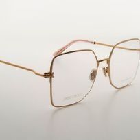 Un par de gafas cuadradas con marco dorado sobre una superficie blanca.