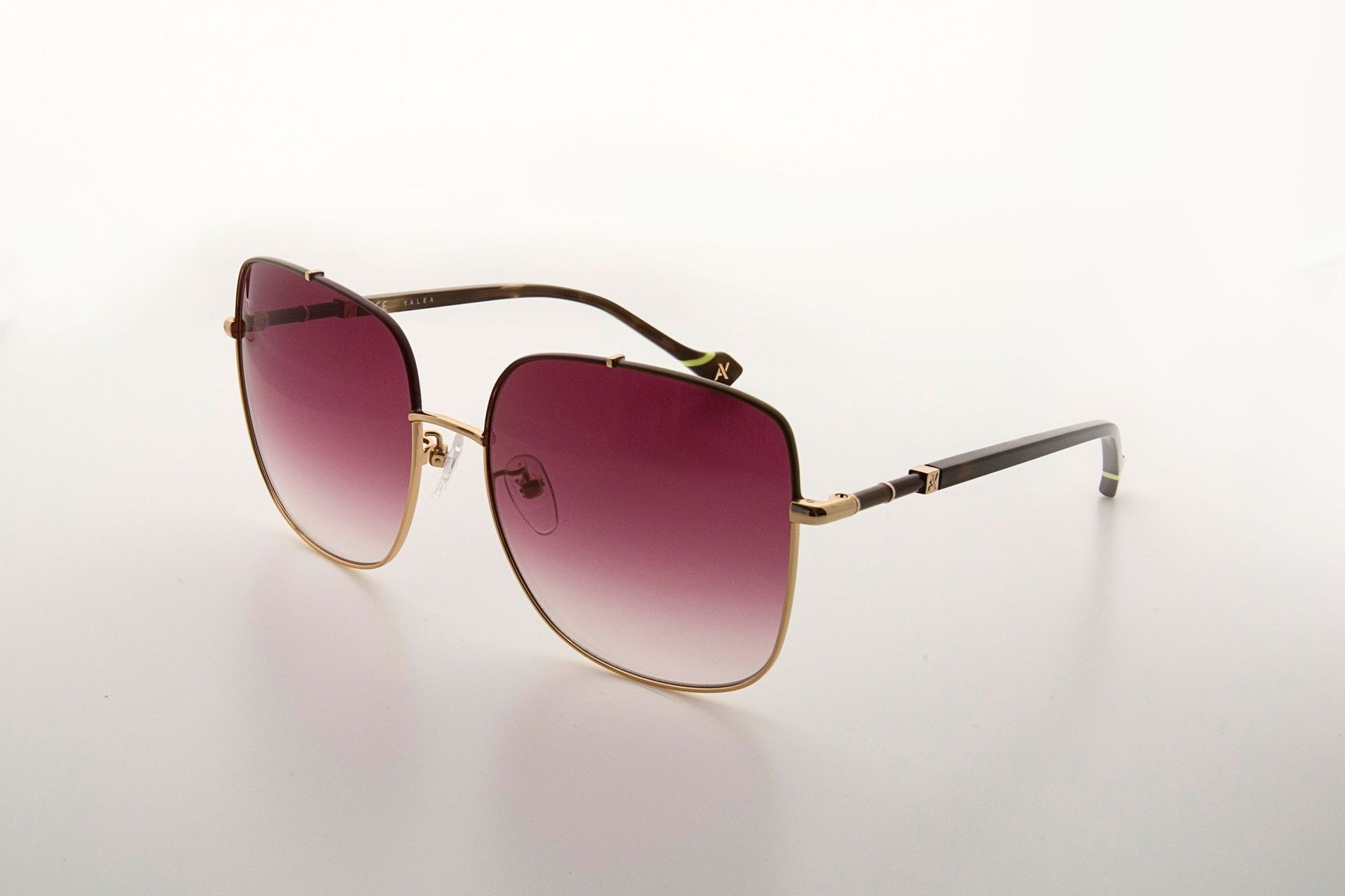 Un par de gafas de sol con lentes de color morado sobre una superficie blanca.