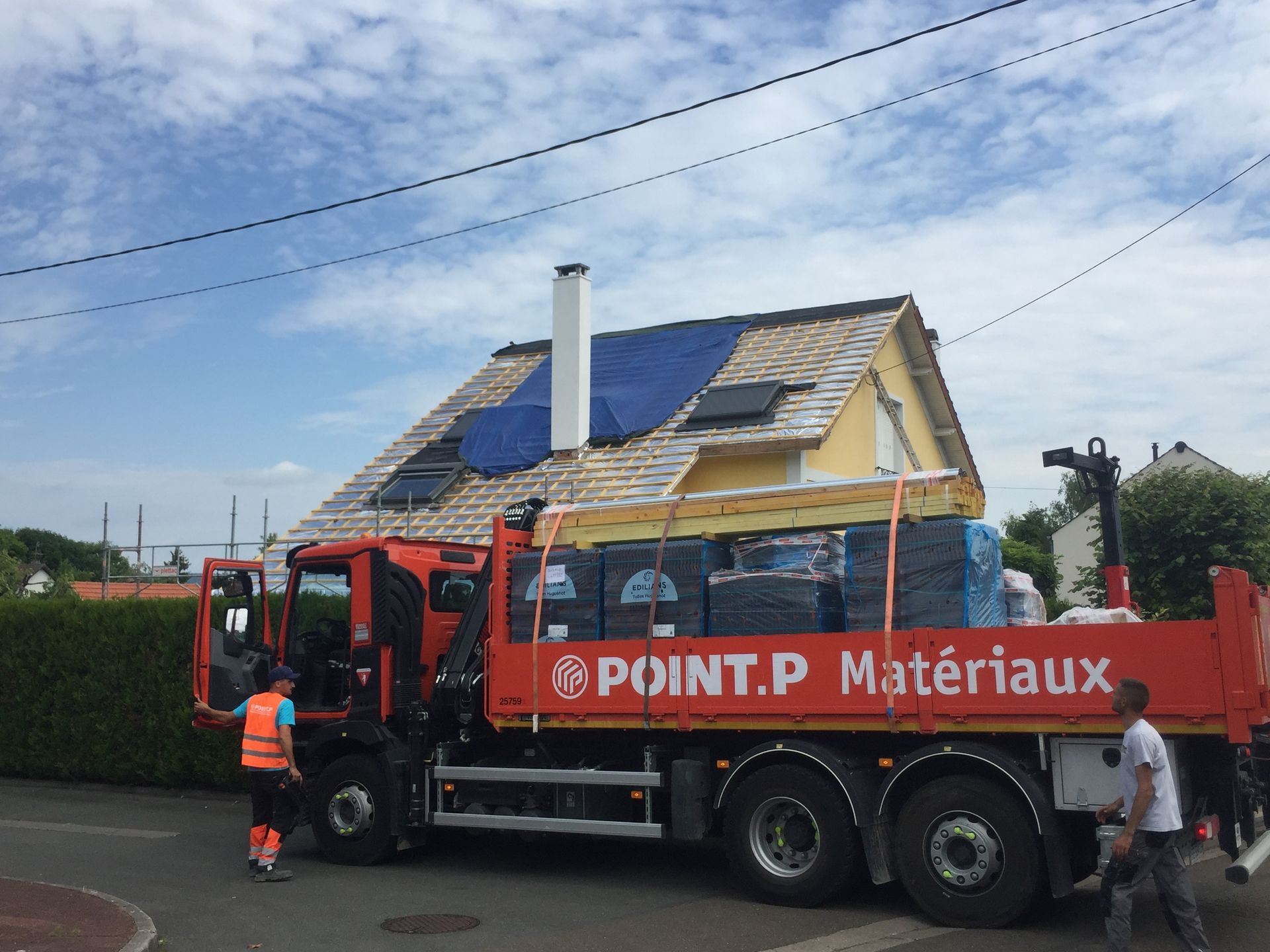 Chantier d'installation de couverture en plan large avec au premier plan un camion floqué Point.P Matériaux