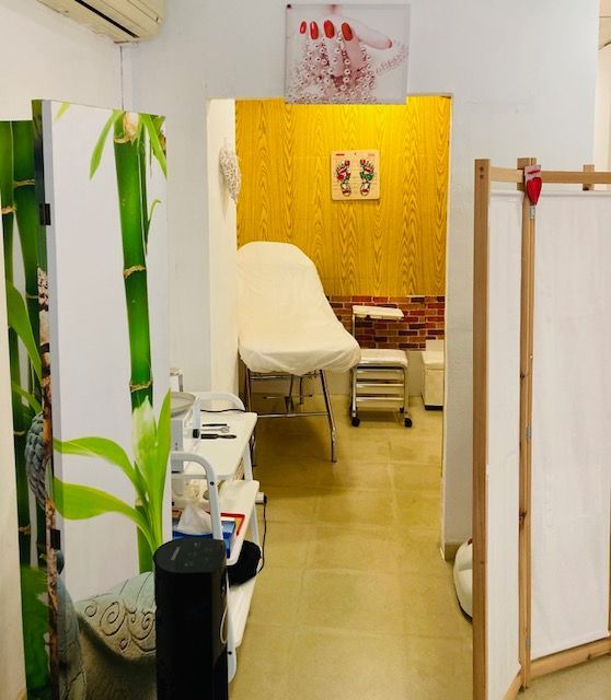 Interior de salón de pedicura con silla blanca, mampara de bambú y pared con acento amarillo.