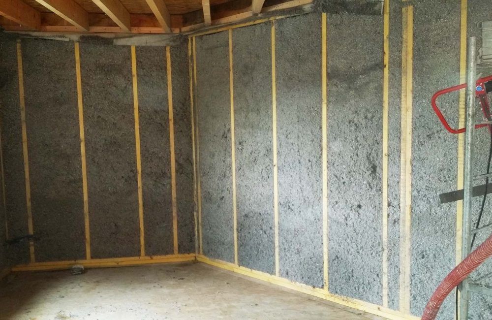 Construction des murs intérieurs : montants en bois apparents avec isolation grise texturée.