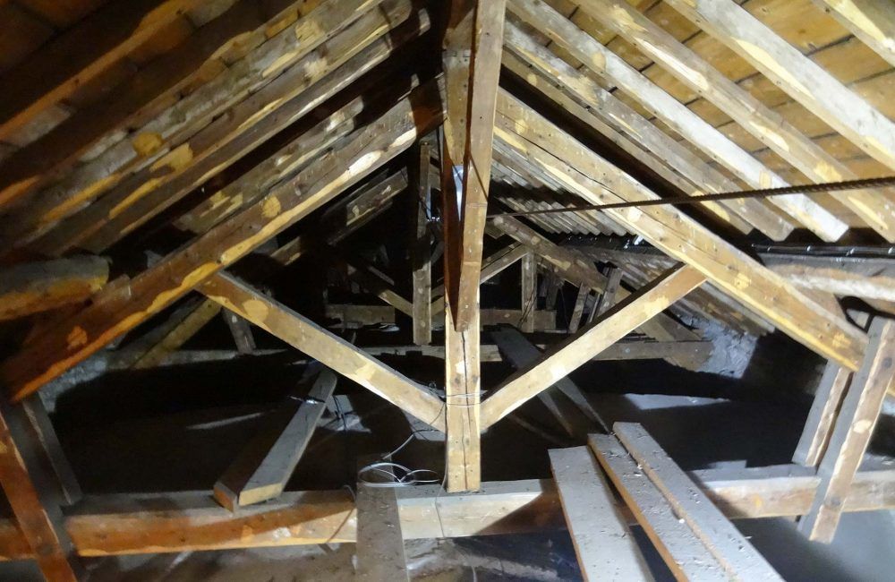 Charpente en bois des combles, composée de poutres, de chevrons et de structures de soutien, vue d'en dessous.