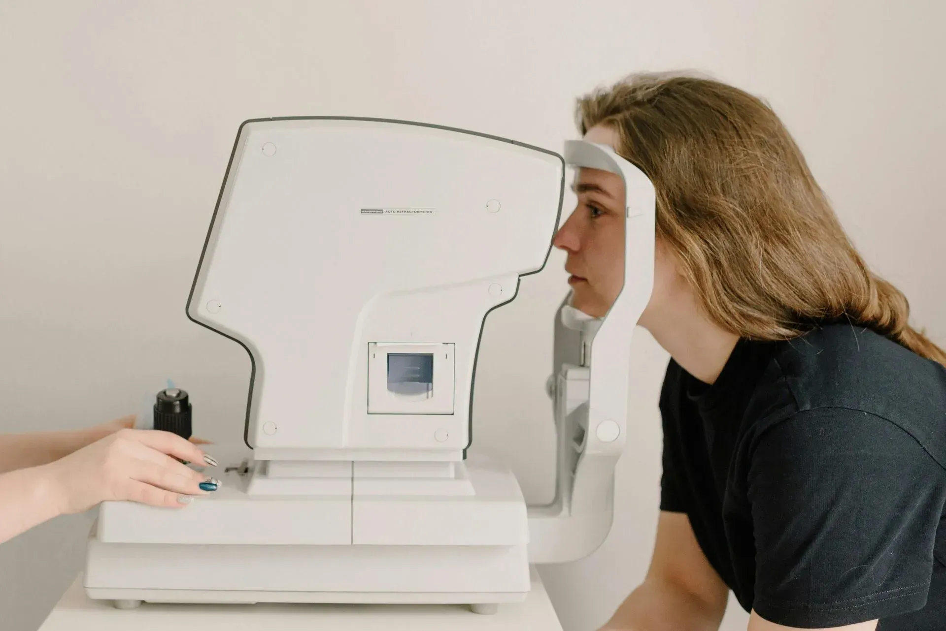 Persona que se somete a un examen ocular utilizando un dispositivo autorrefractor en un entorno clínico.