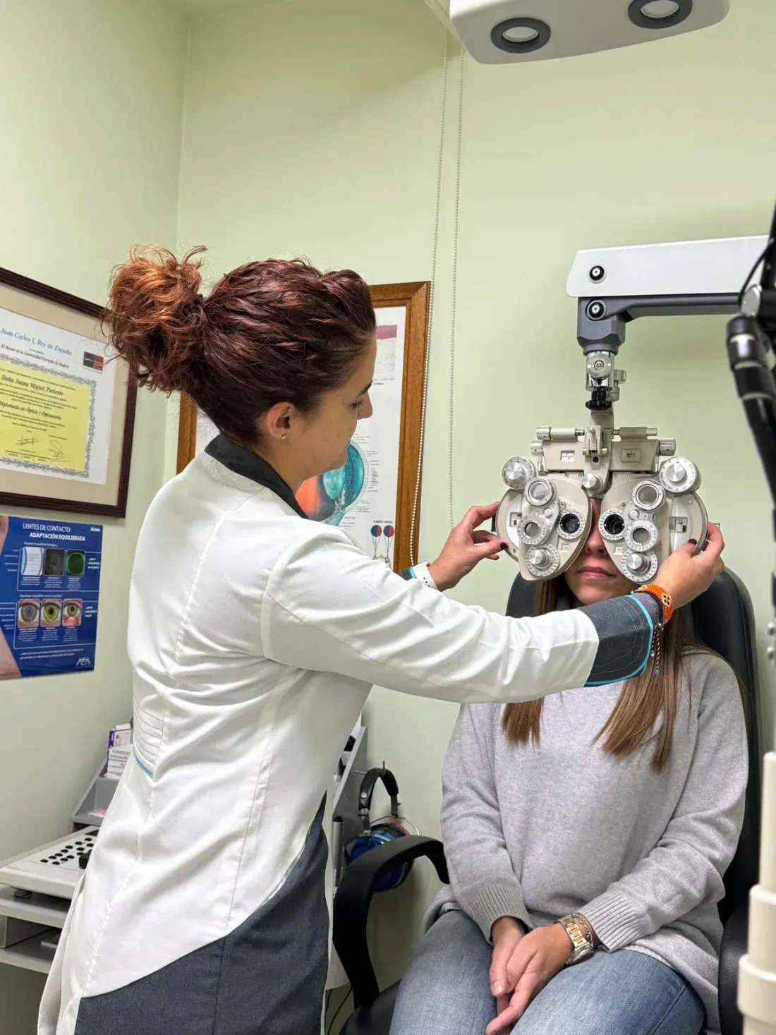 Optometrista realizando un examen ocular a un paciente con un foróptero en una clínica.