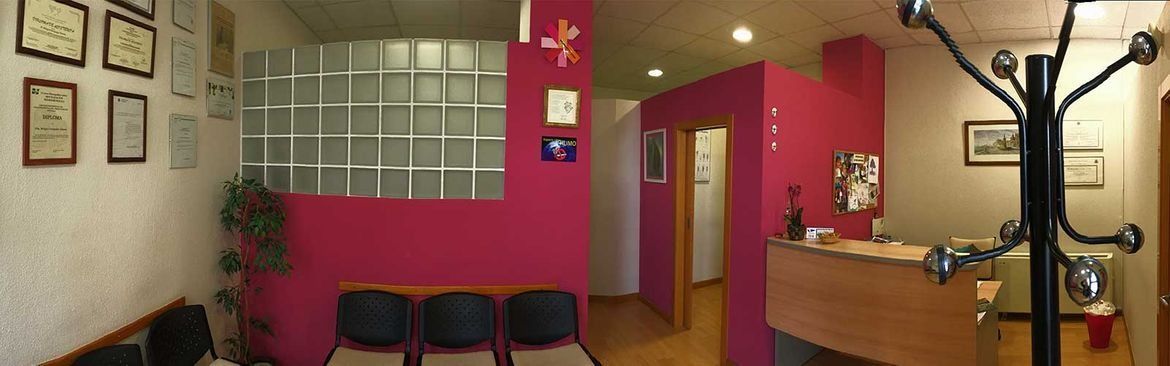 Una sala de espera con paredes rosas y un perchero negro.