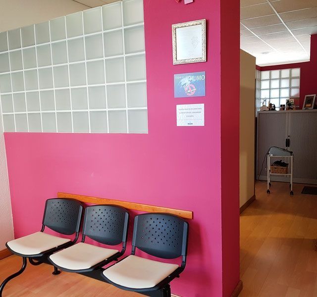 Una fila de sillas en una habitación con una pared rosa.