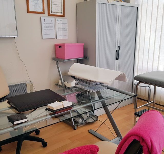 Una habitación con un escritorio de cristal y una silla rosa.