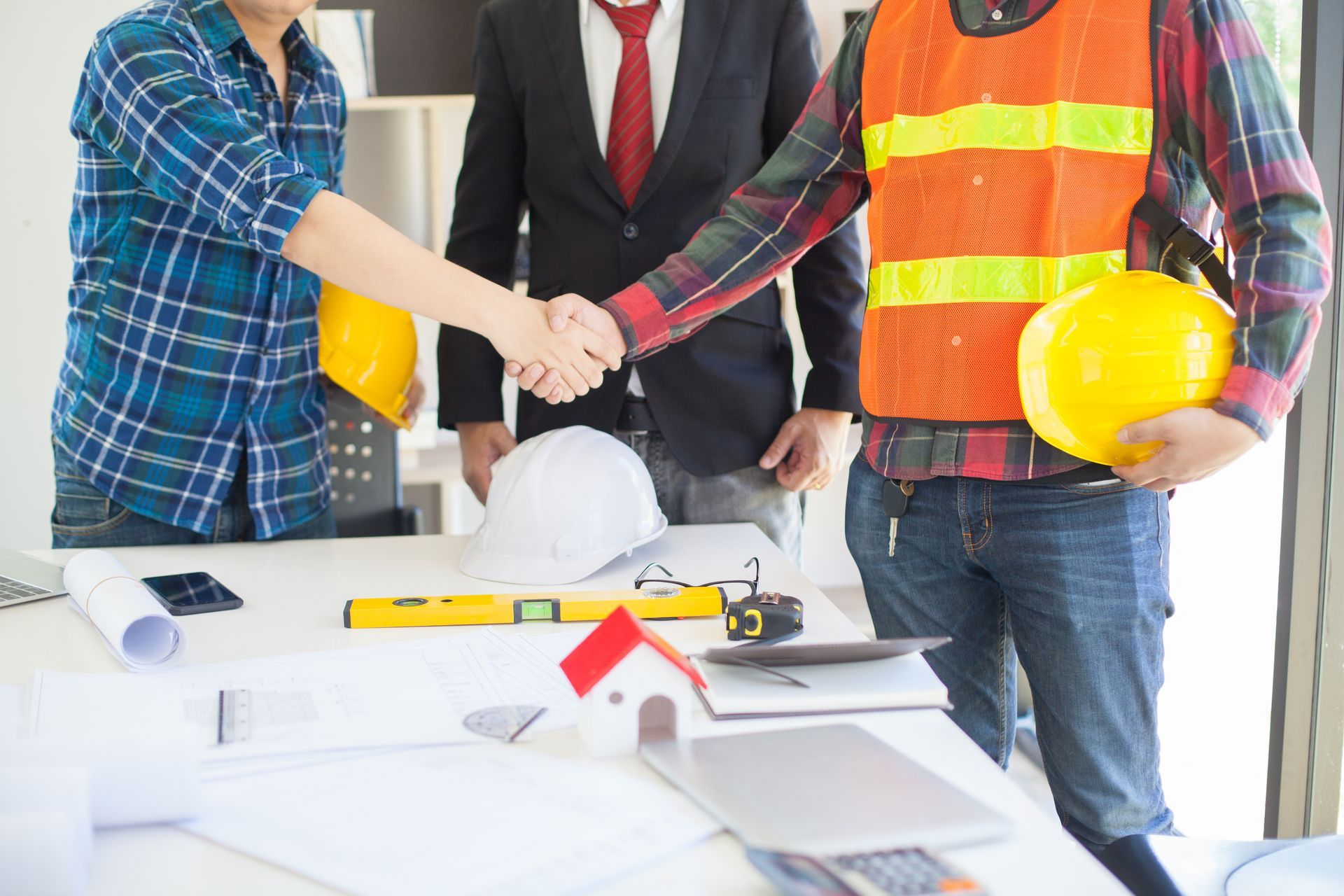 Un groupe d'ouvriers du bâtiment serrant la main d'un homme en costume et cravate.