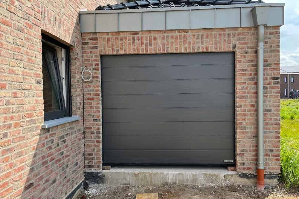 Graues Garagentor an einem Backsteingebäude.