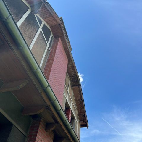 Vue en contre-plongée d'un bâtiment en briques rouges avec des fenêtres se détachant sur un ciel bleu éclatant.
