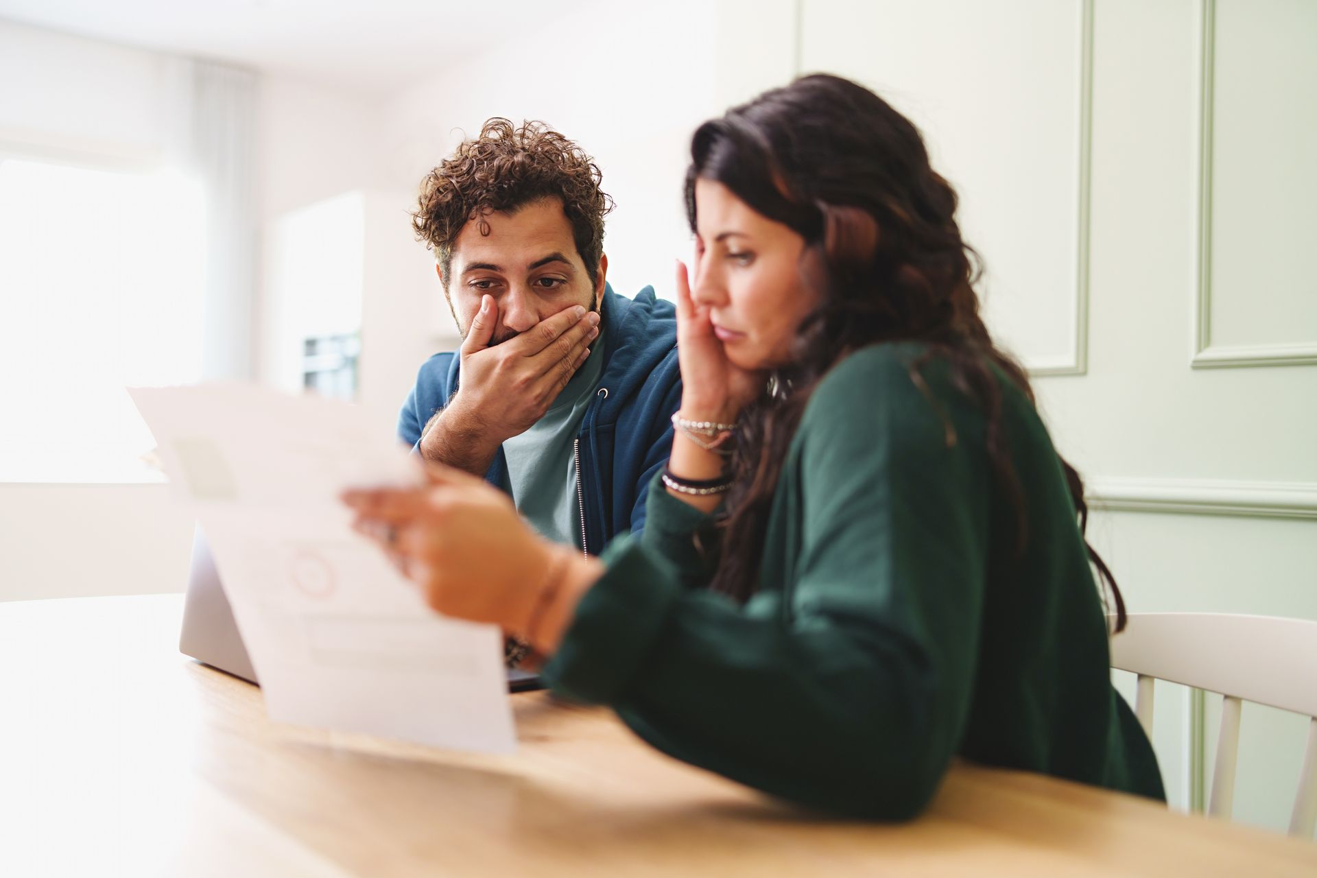 Deux personnes examinent un document à une table : l’une tient la feuille tandis que l’autre l’observe d’un air pensif