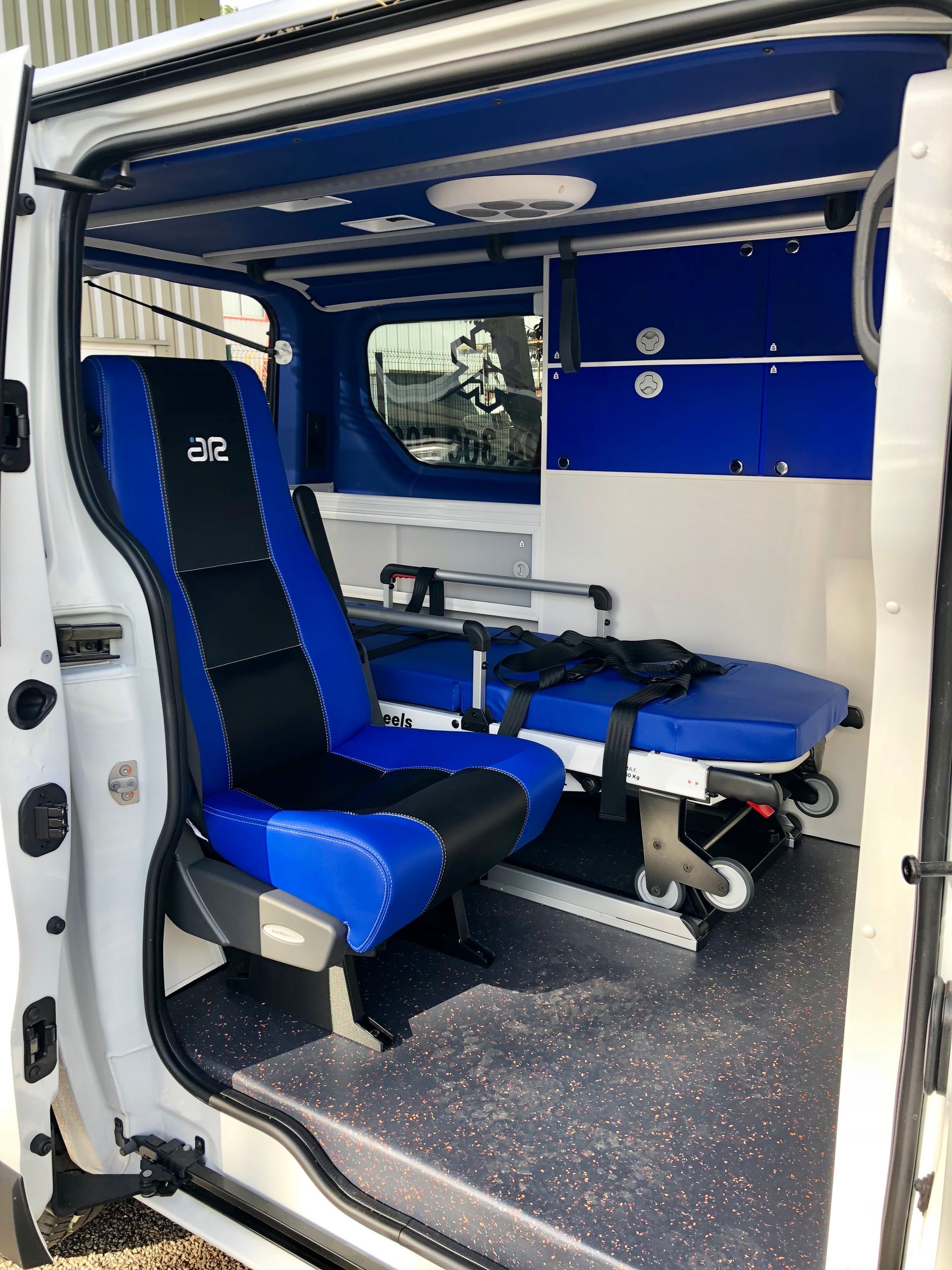 Porte ouverte d'une ambulance de Var Assistance montrant le siège et le brancard à l'intérieur