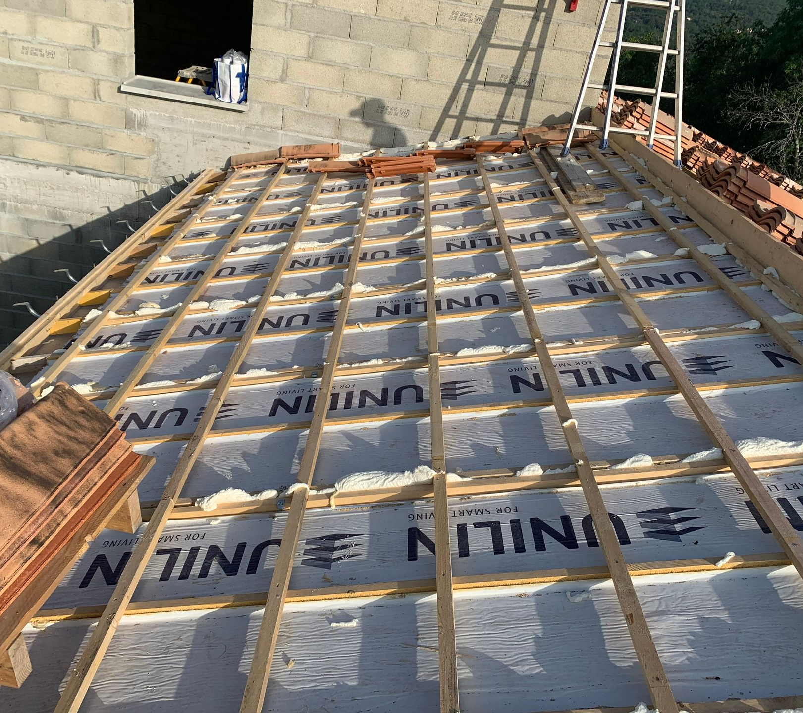 Voiture blanche garée sous un abri en bois avec une allée en gravier.