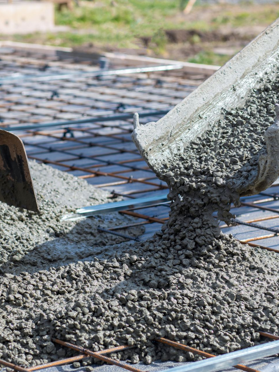 Du béton coule sur une grille d'armature, préparant des fondations.
