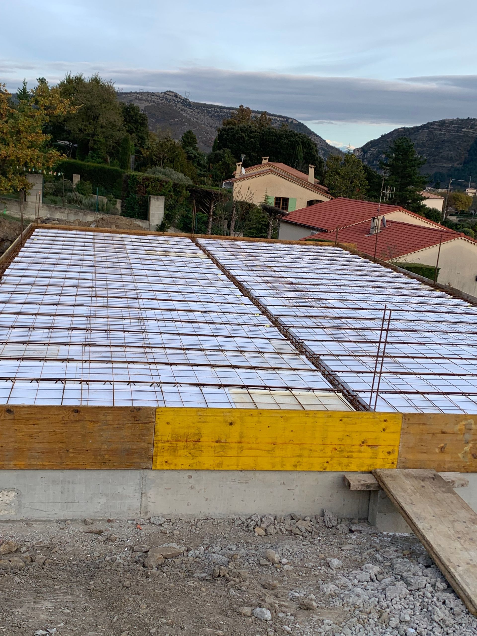 Coffrage d'une dalle en béton avec poutres en bois et panneaux blancs.