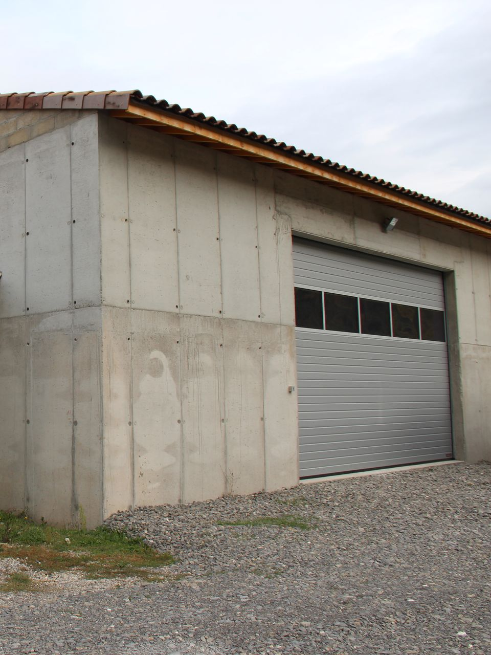 Bâtiment en béton avec porte de garage enroulable.