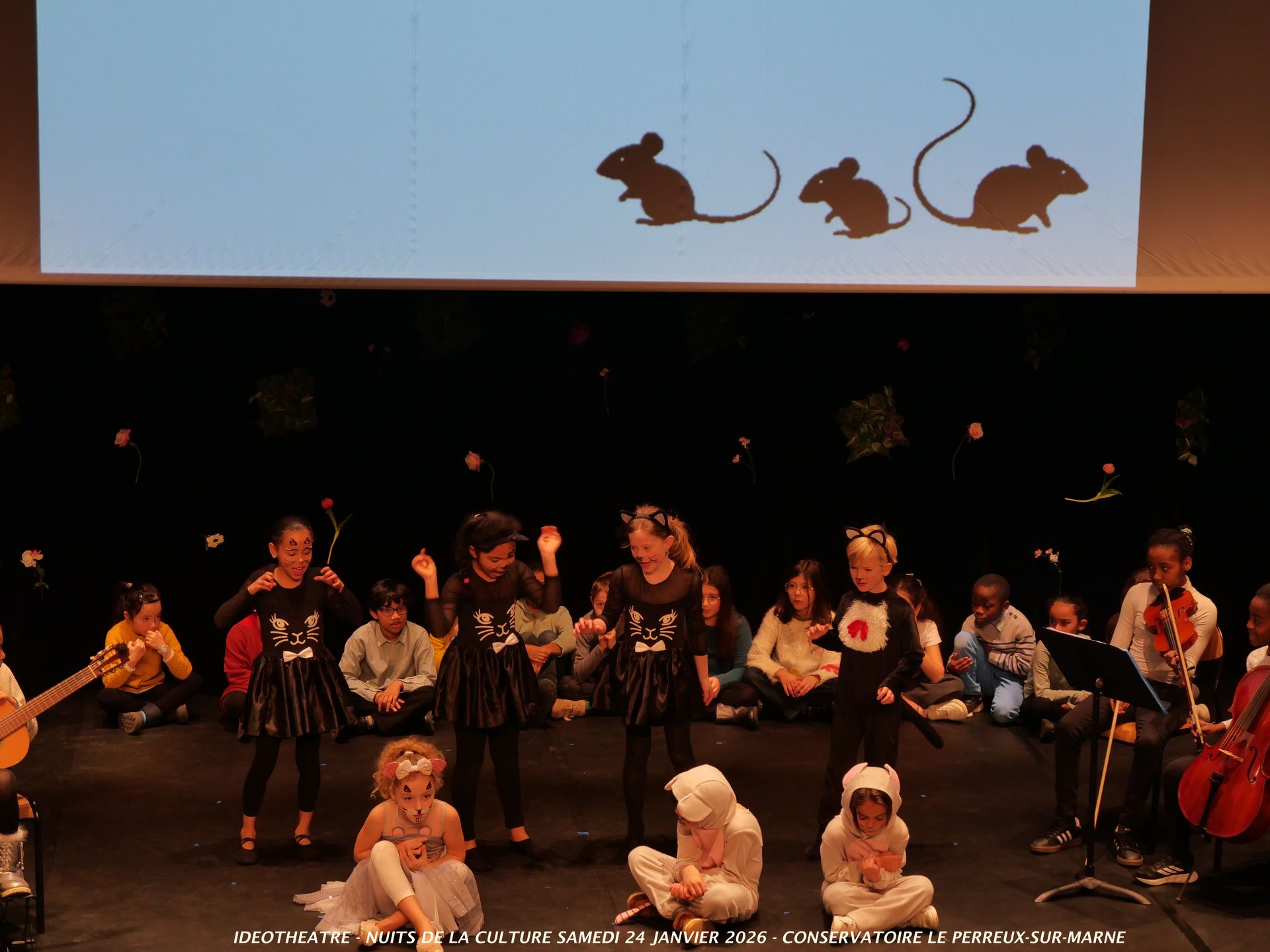 Spectacle pour enfants avec des acteurs costumés et des ombres chinoises projetées sur un écran.