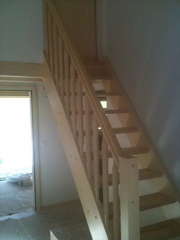 Escalier en bois à marches ouvertes dans une pièce inachevée à côté d'une porte