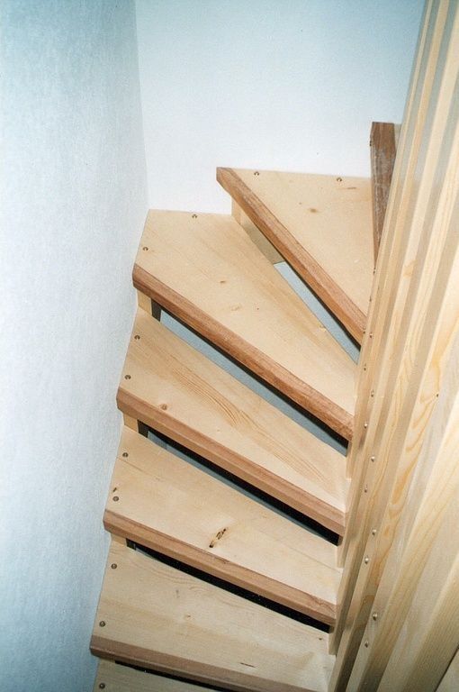 Escalier étroit en colimaçon de bois dans un coin intérieur blanc