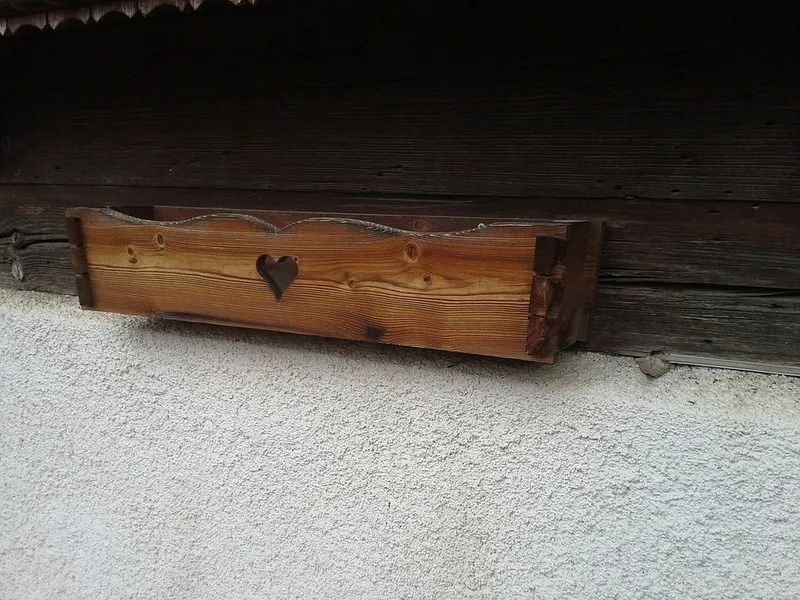 Boîte murale en bois avec une découpe en forme de cœur sur un mur en stuc blanc