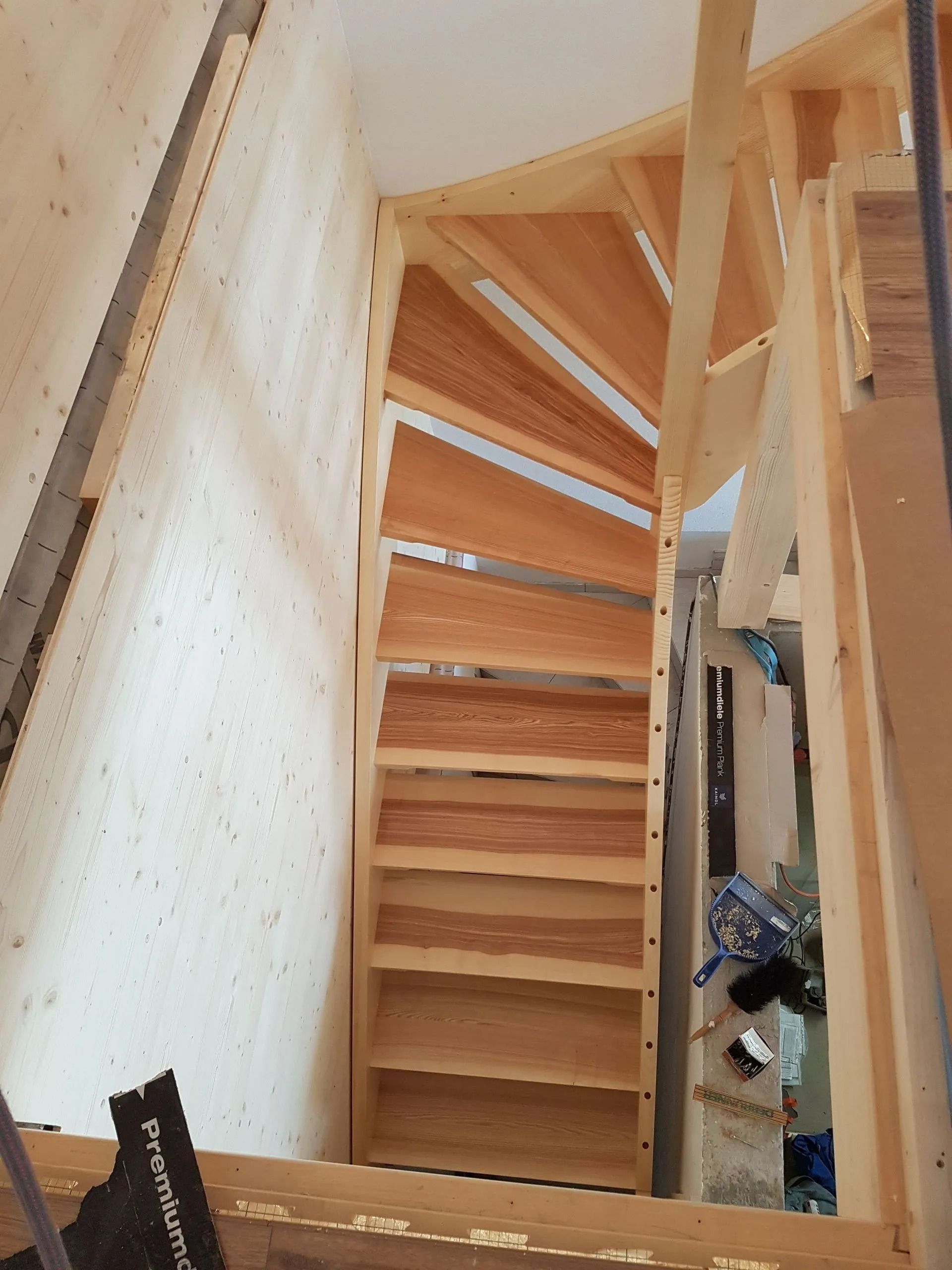 Escalier intérieur étroit en bois avec contremarches ouvertes et murs clairs dans un espace exigu
